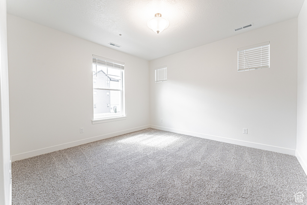 Carpeted spare room featuring baseboards