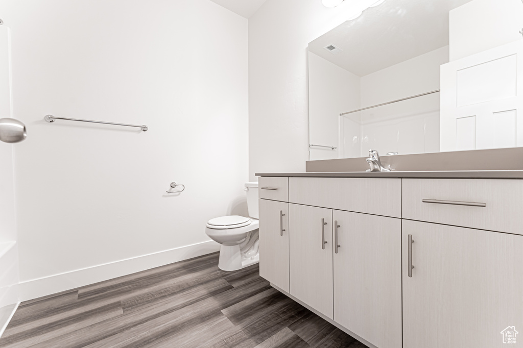 Full bath featuring vanity, toilet, baseboards, wood finished floors, and a shower