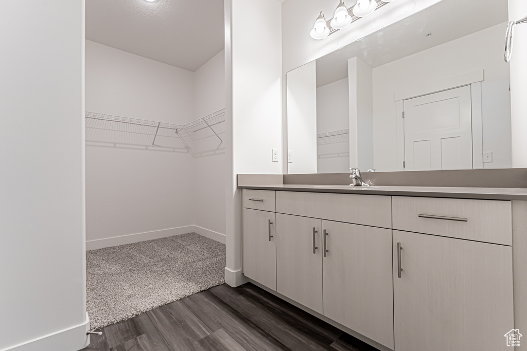 Bathroom featuring vanity, wood finished floors, a walk in closet, and baseboards