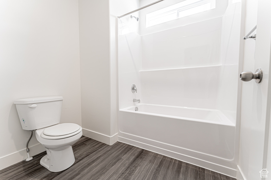 Full bath with toilet, wood finished floors, baseboards, and shower / bathtub combination