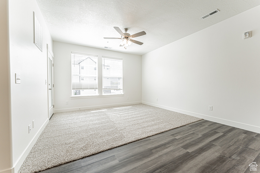 Empty room featuring a ceiling fan, wood finished floors, baseboards, and a textured ceiling
