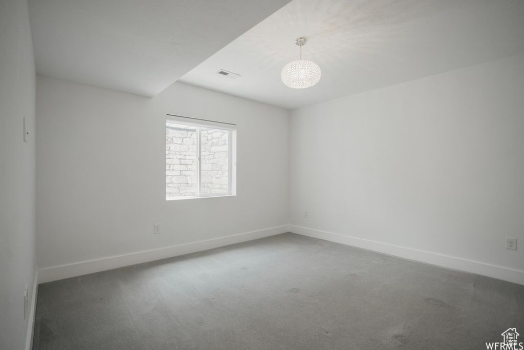Empty room with dark carpet and a notable chandelier