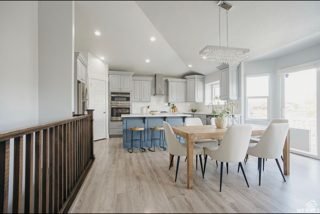 Dining area with a notable chandelier, lofted ceiling, and light hardwood / wood-style flooring