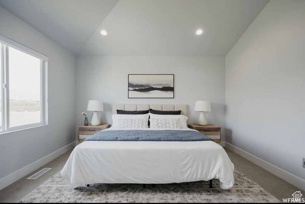 Bedroom featuring carpet flooring, lofted ceiling, and multiple windows