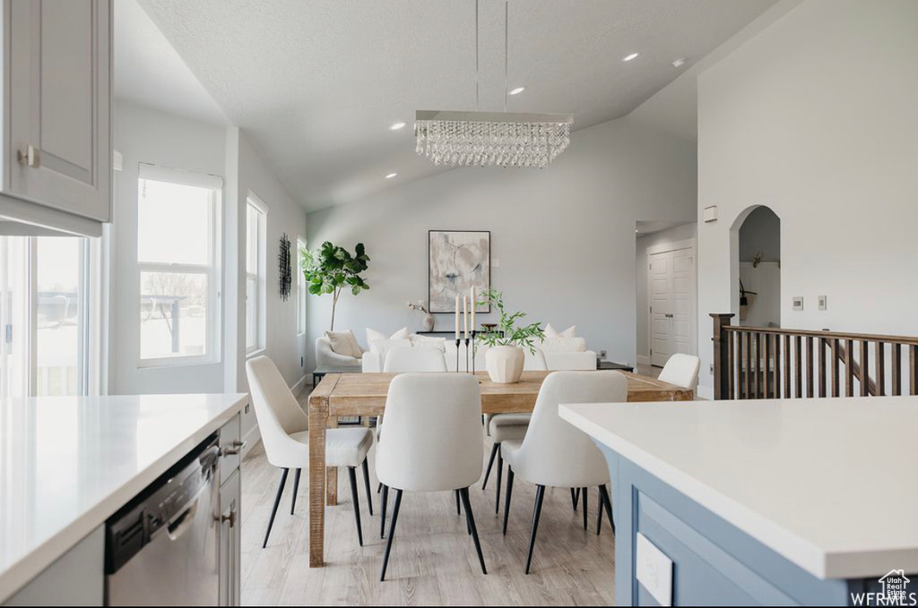 Dining room featuring light wood-type flooring, lofted ceiling, and a notable chandelier