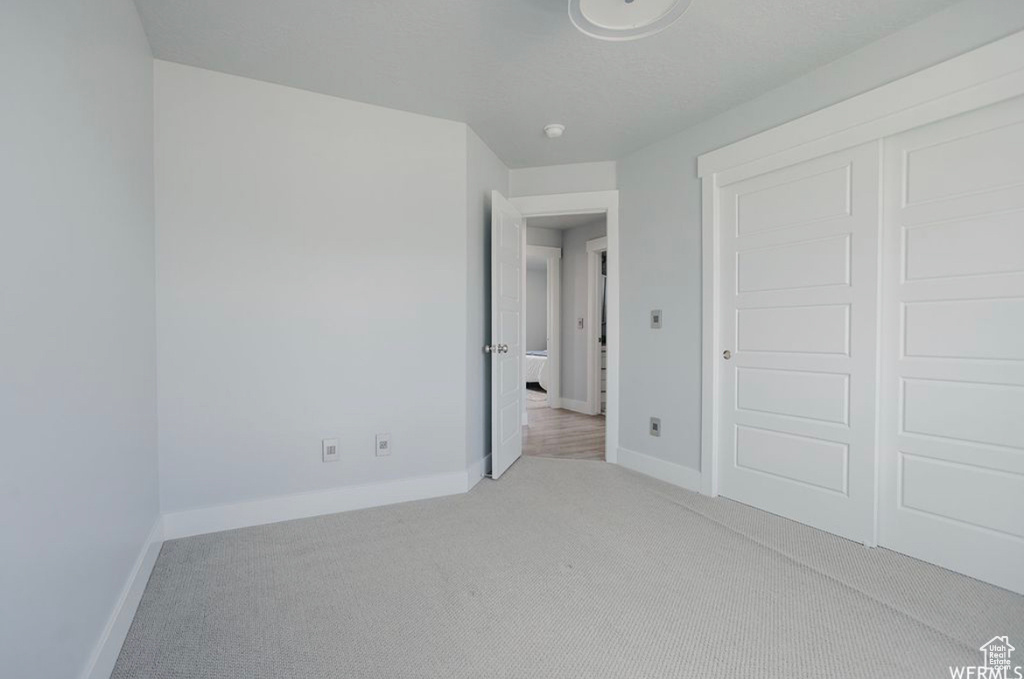 Unfurnished bedroom featuring a closet and light colored carpet