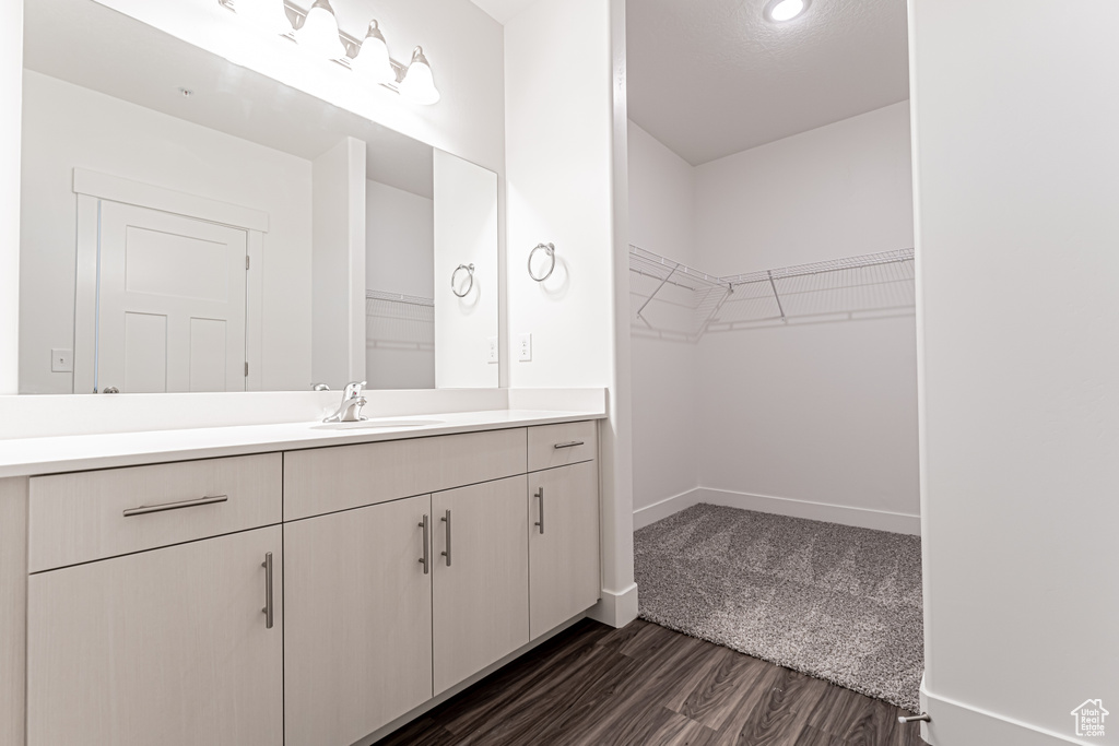 Bathroom with vanity, wood finished floors, a spacious closet, and baseboards