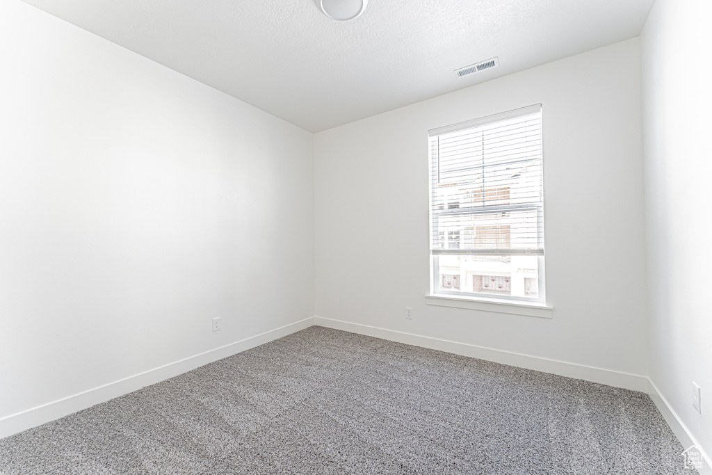 Carpeted spare room featuring baseboards and a textured ceiling