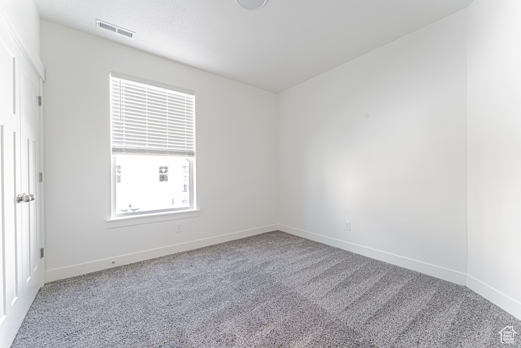 Carpeted spare room featuring baseboards