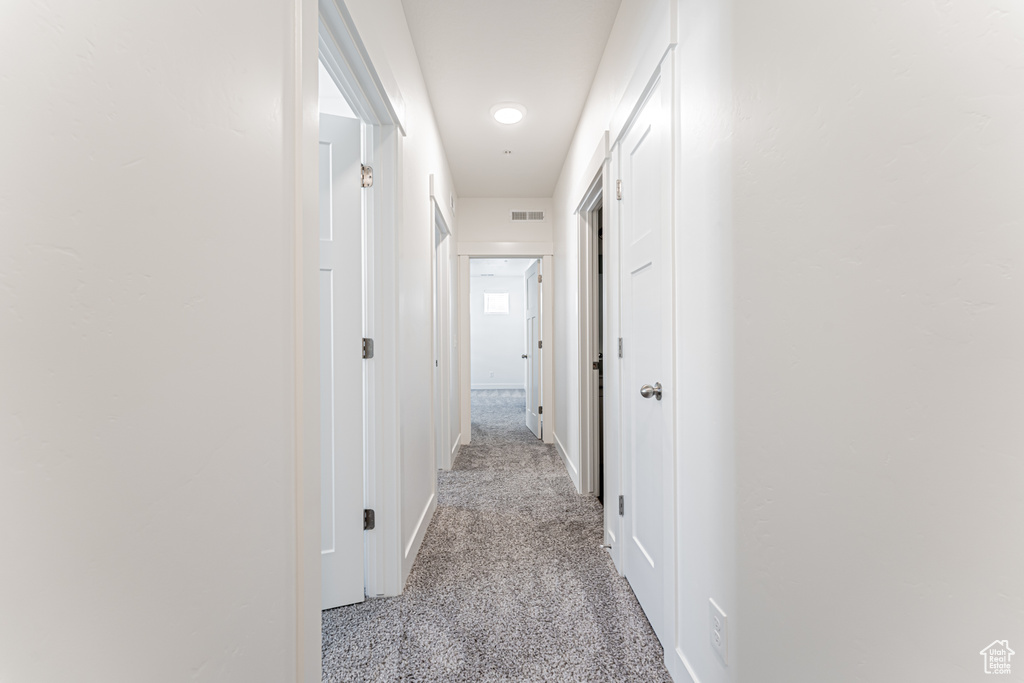 Hallway with baseboards and light carpet