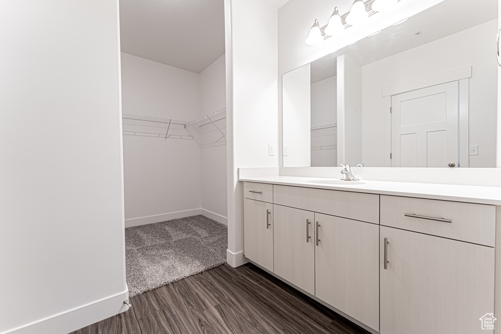 Bathroom with vanity, a walk in closet, baseboards, and wood finished floors