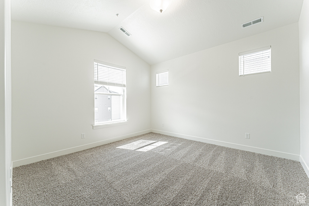 Spare room with carpet flooring, baseboards, and vaulted ceiling