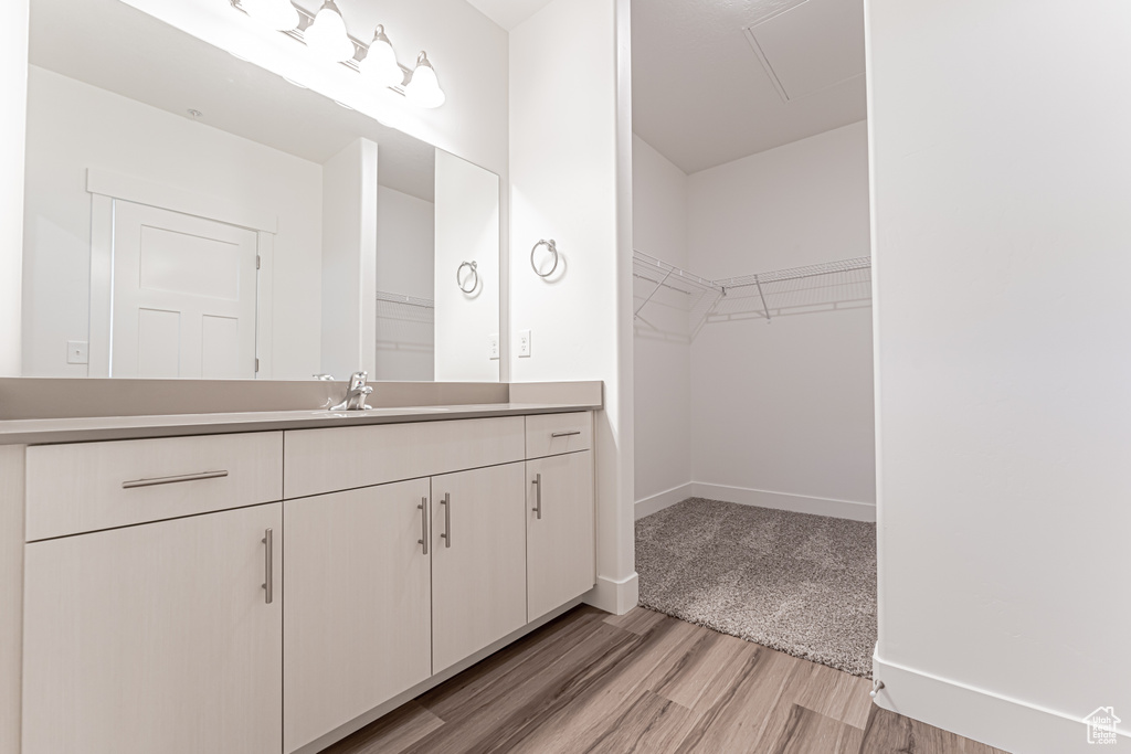 Bathroom with vanity, wood finished floors, a spacious closet, and baseboards