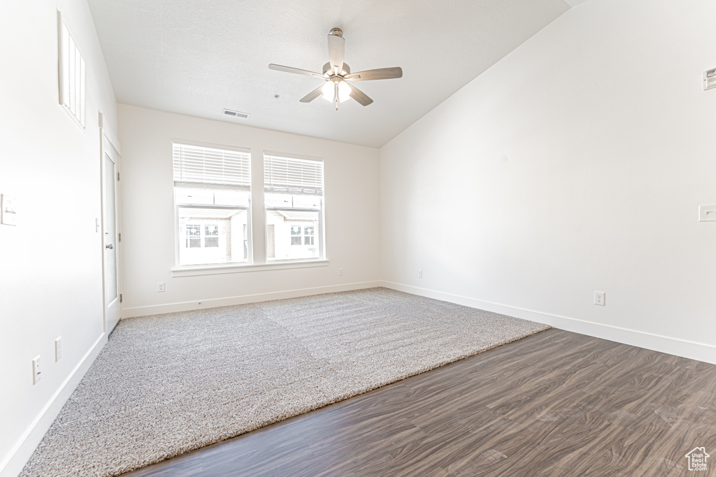 Unfurnished room with ceiling fan, vaulted ceiling, wood finished floors, and baseboards