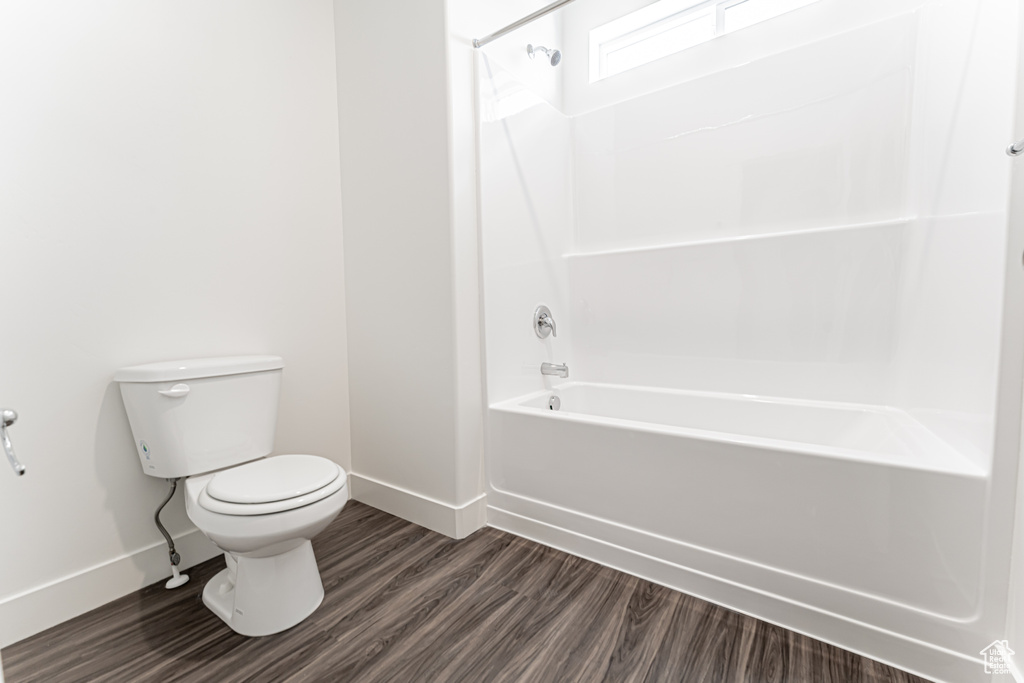 Full bathroom with baseboards, toilet, shower / bathtub combination, and wood finished floors