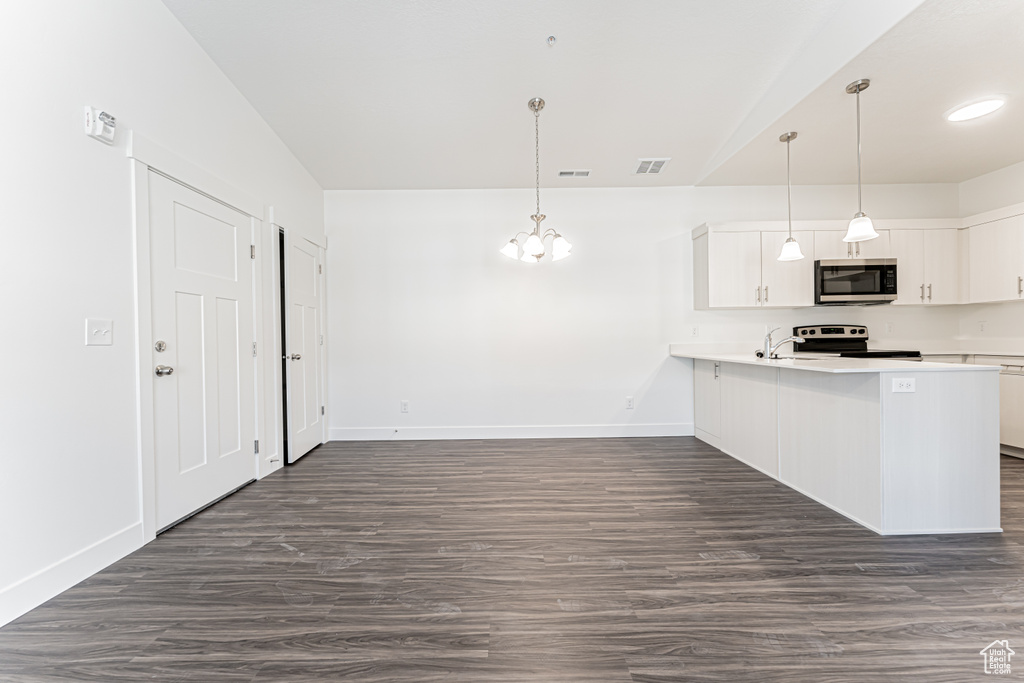 Kitchen with appliances with stainless steel finishes, white cabinetry, light countertops, and baseboards