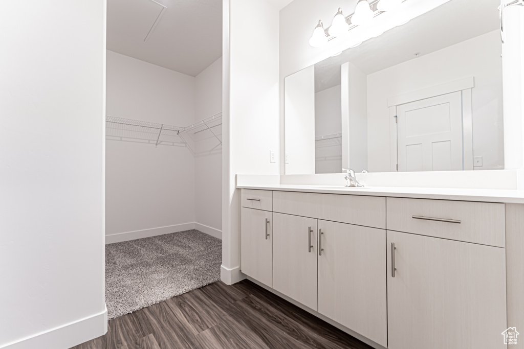 Bathroom featuring vanity, wood finished floors, a walk in closet, and baseboards
