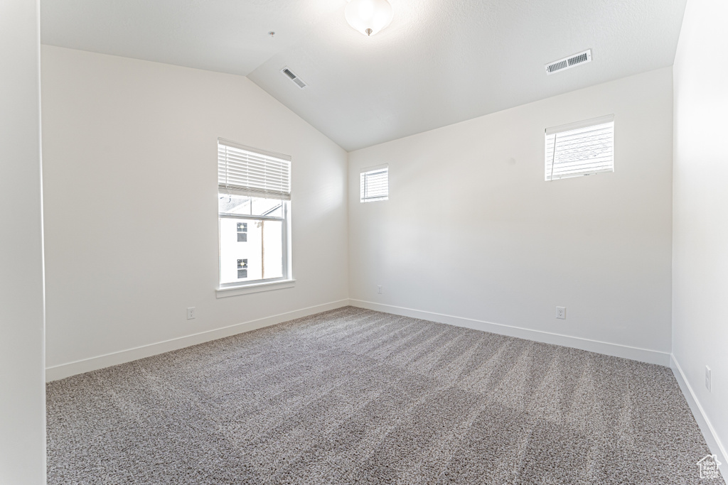 Spare room featuring carpet, lofted ceiling, and baseboards