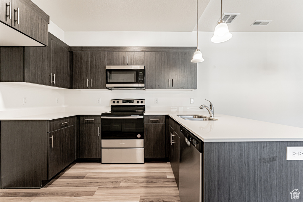 Kitchen with stainless steel appliances, a sink, light countertops, and a peninsula