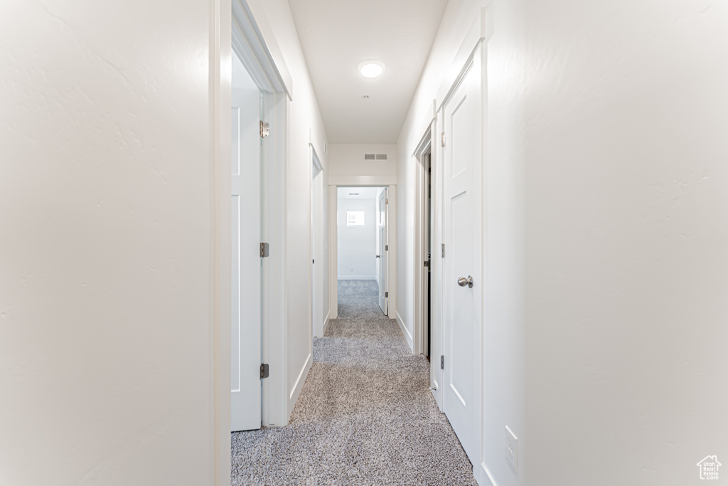 Hall featuring light colored carpet and baseboards
