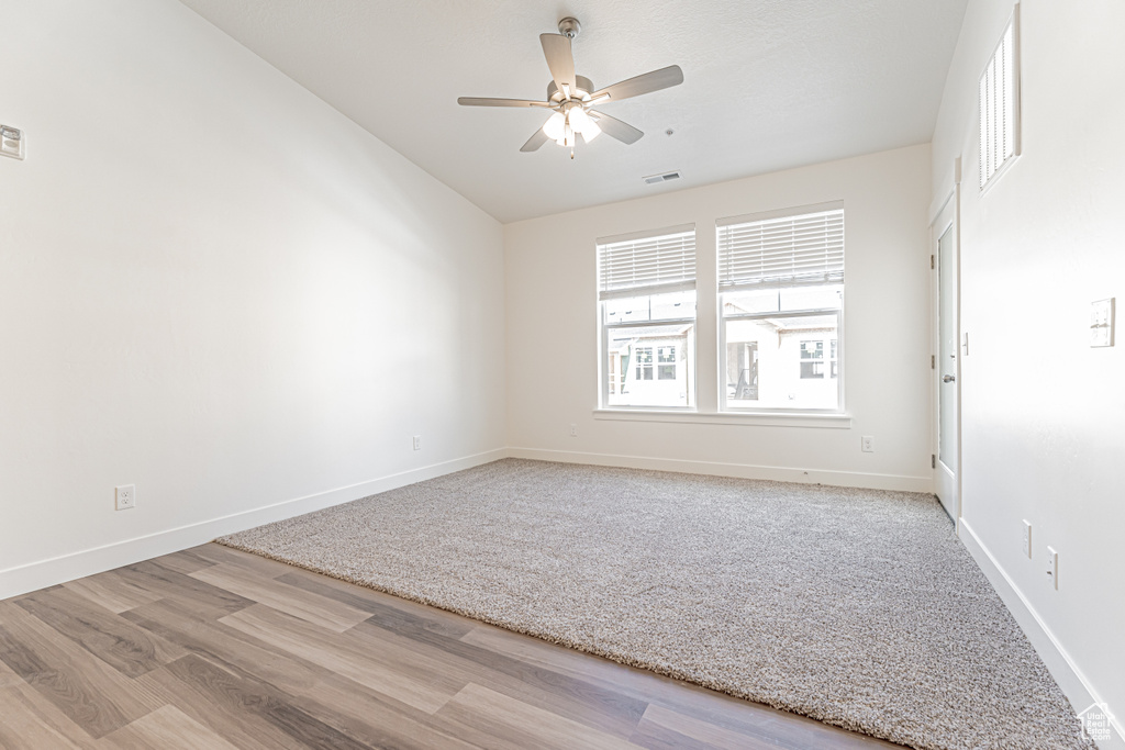 Spare room with wood finished floors, a ceiling fan, and baseboards