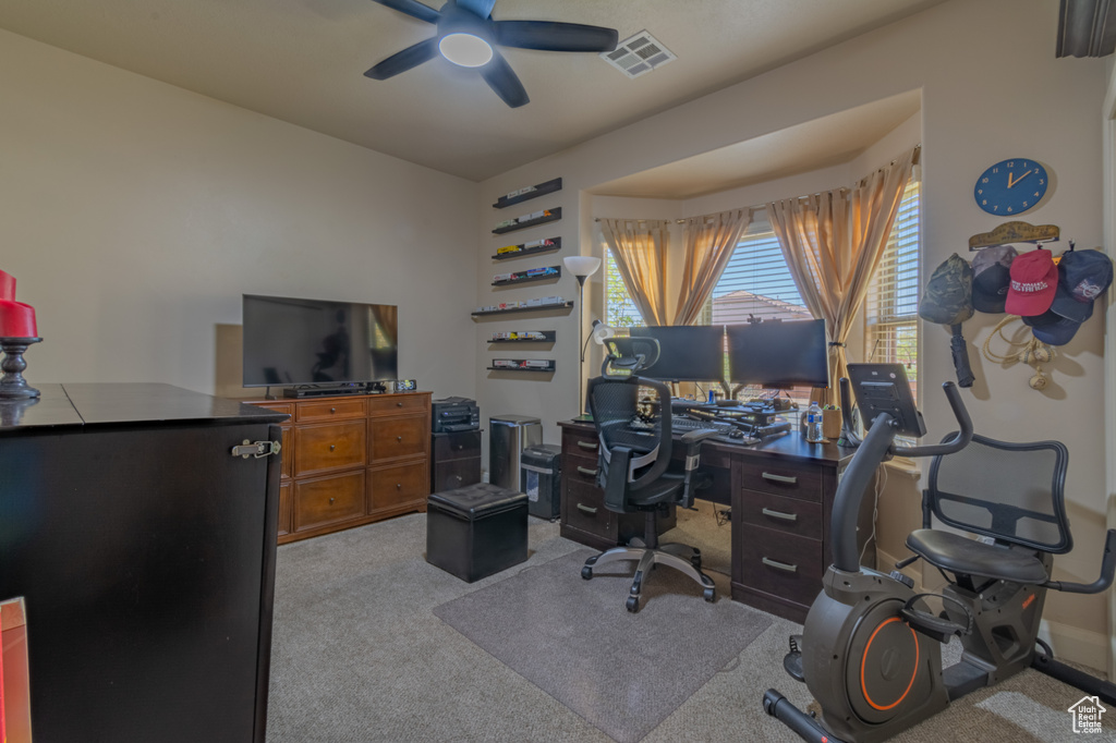 Carpeted office featuring ceiling fan