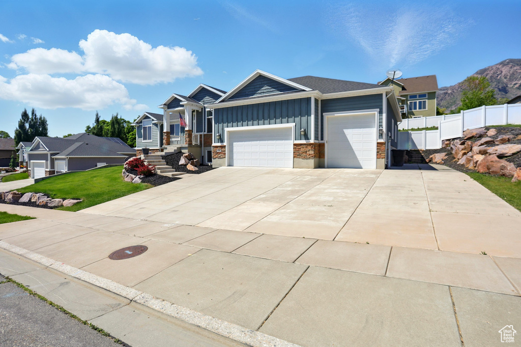 View of front of property featuring board and batten siding, a garage, driveway, and stone siding