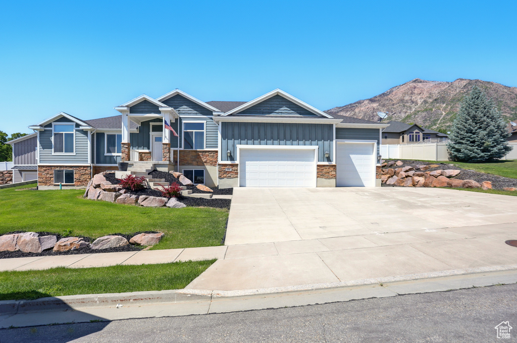 Craftsman-style home featuring a garage, board and batten siding, stone siding, a front yard, and driveway