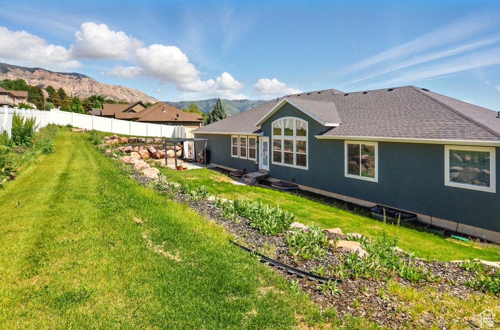 Rear view of property with a mountain view, a patio area, roof with shingles, and stucco siding