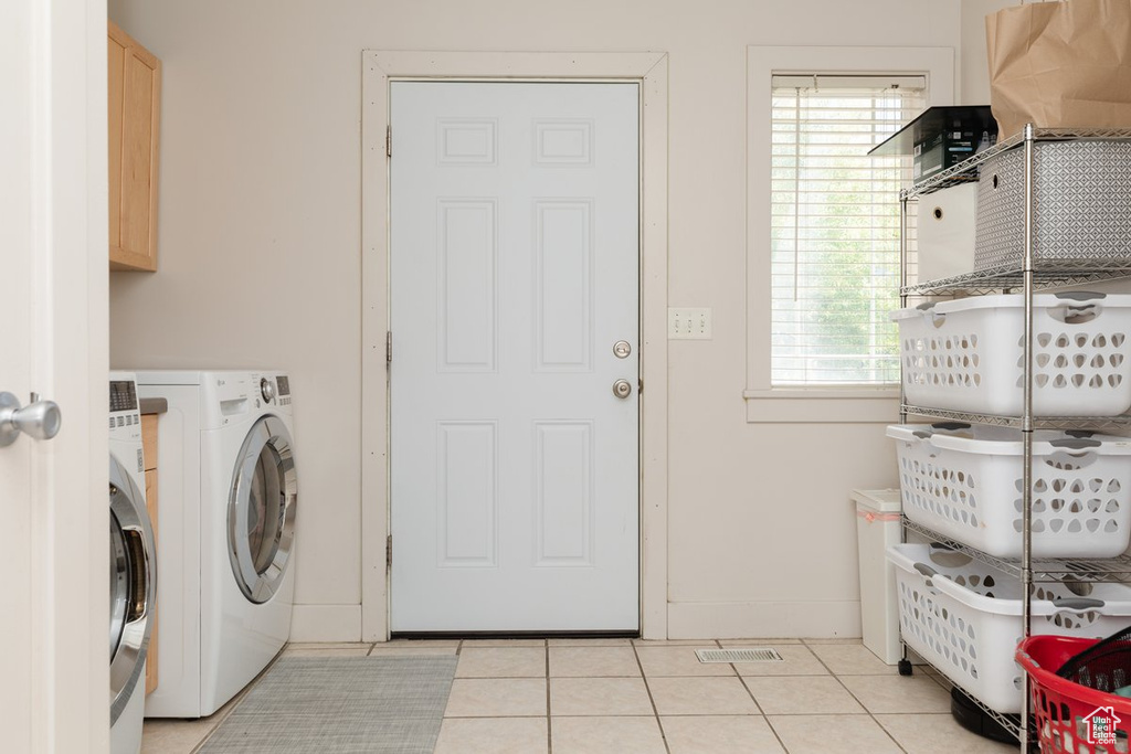 Washroom with light tile patterned flooring, cabinets, and a healthy amount of sunlight