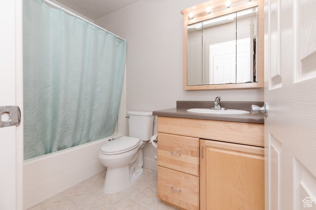 Full bathroom with tile patterned flooring, shower / tub combo, toilet, and vanity