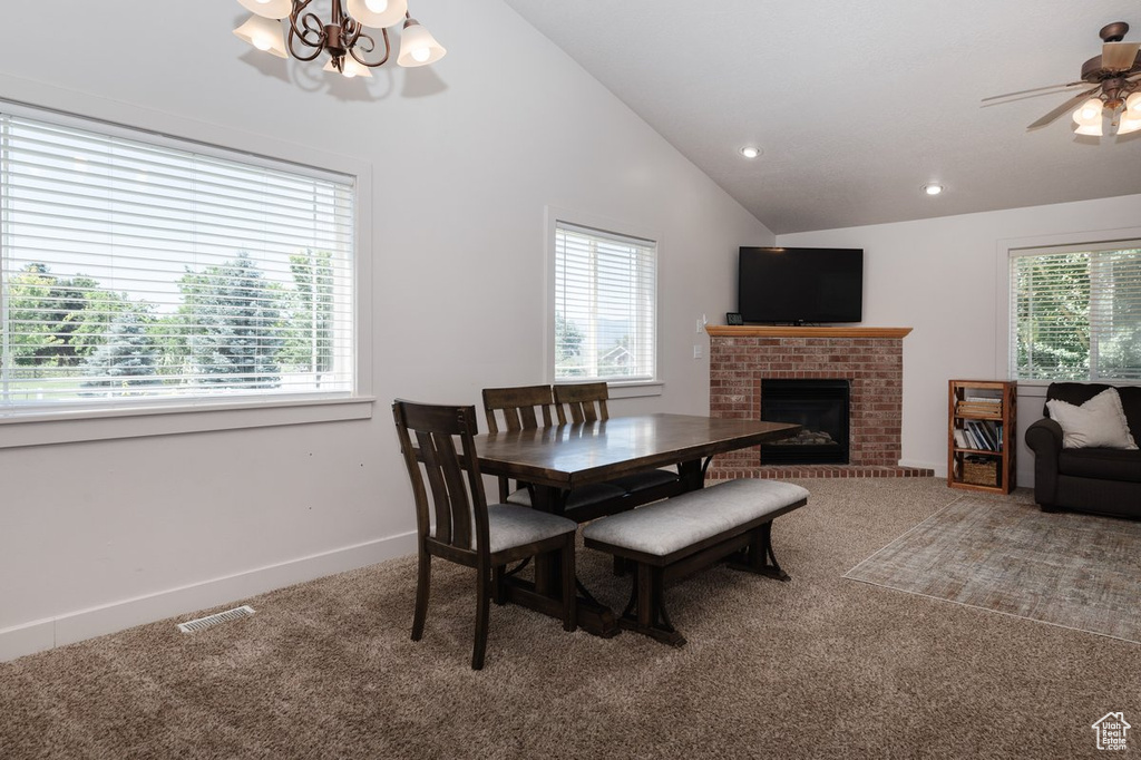 Carpeted dining space with lofted ceiling, a brick fireplace, and ceiling fan