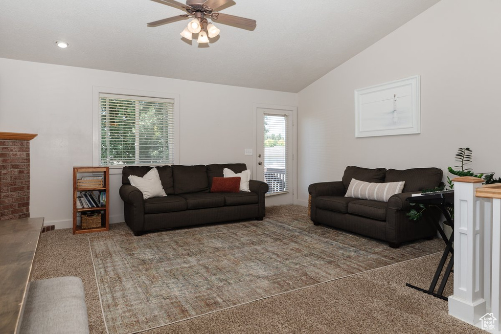 Carpeted living room with lofted ceiling and ceiling fan