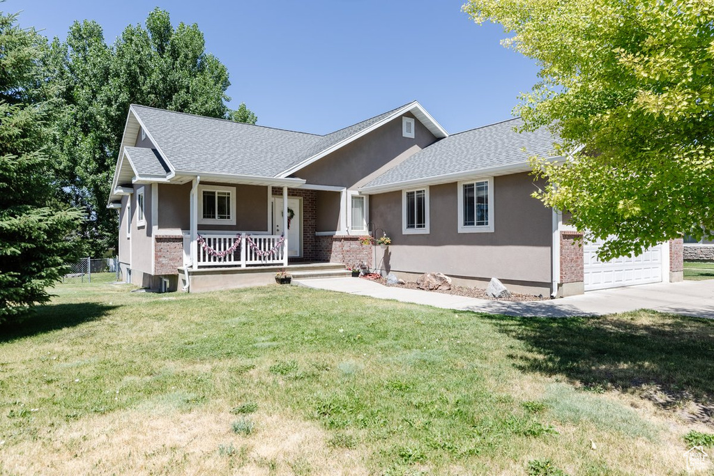 View of front of home featuring a porch, a garage, and a front lawn