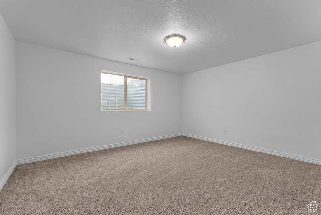 Spare room featuring carpet and a textured ceiling