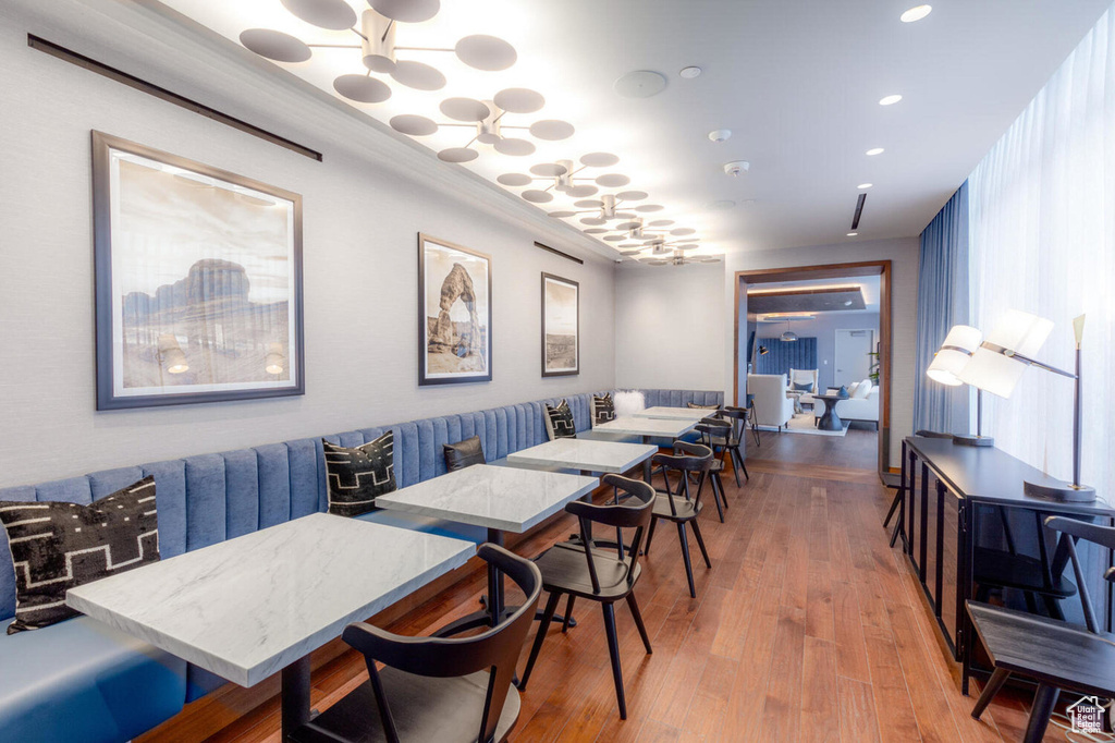 Dining area with wood-type flooring, crown molding, and a notable chandelier