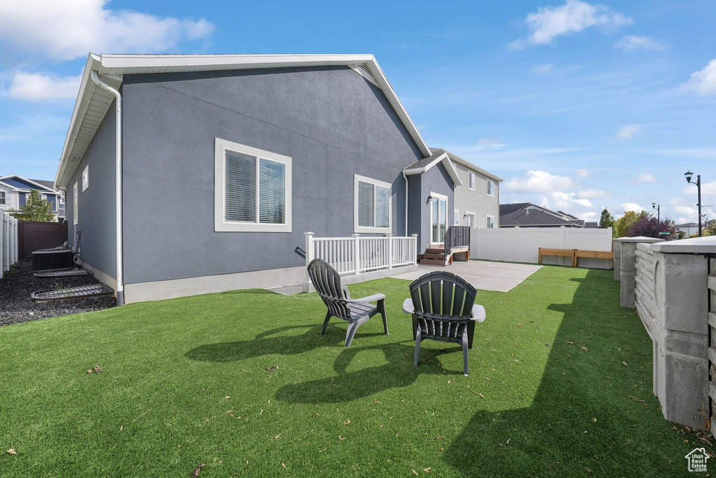 Back of property with a yard, a patio, and central air condition unit