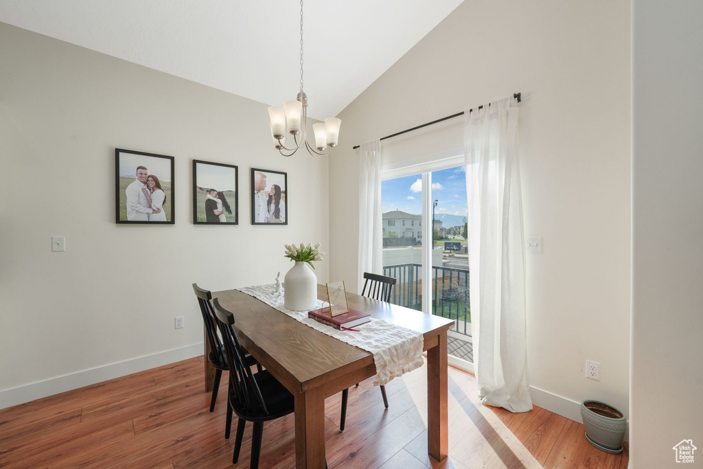 Dining area with hardwood / wood-style floors, a chandelier, and lofted ceiling