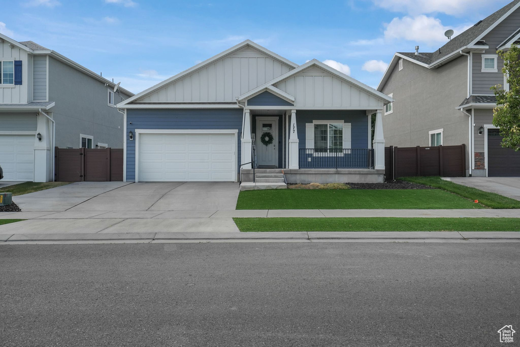 View of front of property with a front yard, a porch, and a garage