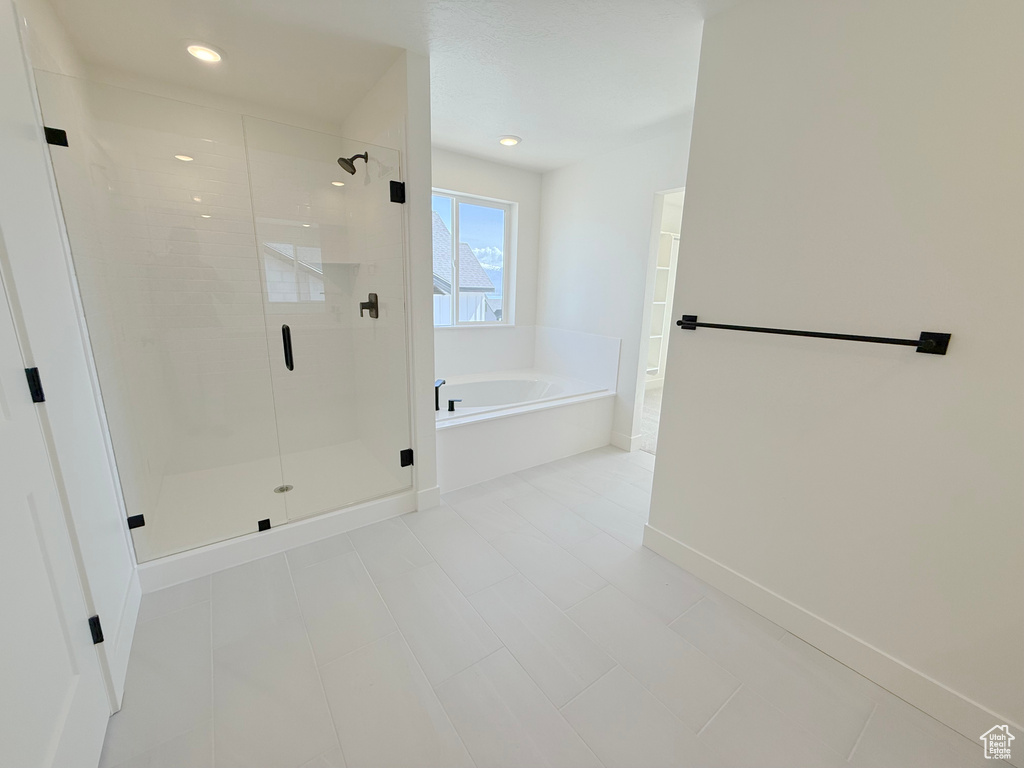 Bathroom featuring a bath, a stall shower, baseboards, and recessed lighting