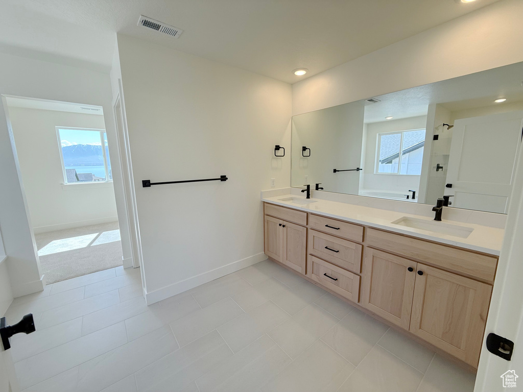 Full bathroom with double vanity, baseboards, recessed lighting, tile patterned flooring, and a shower