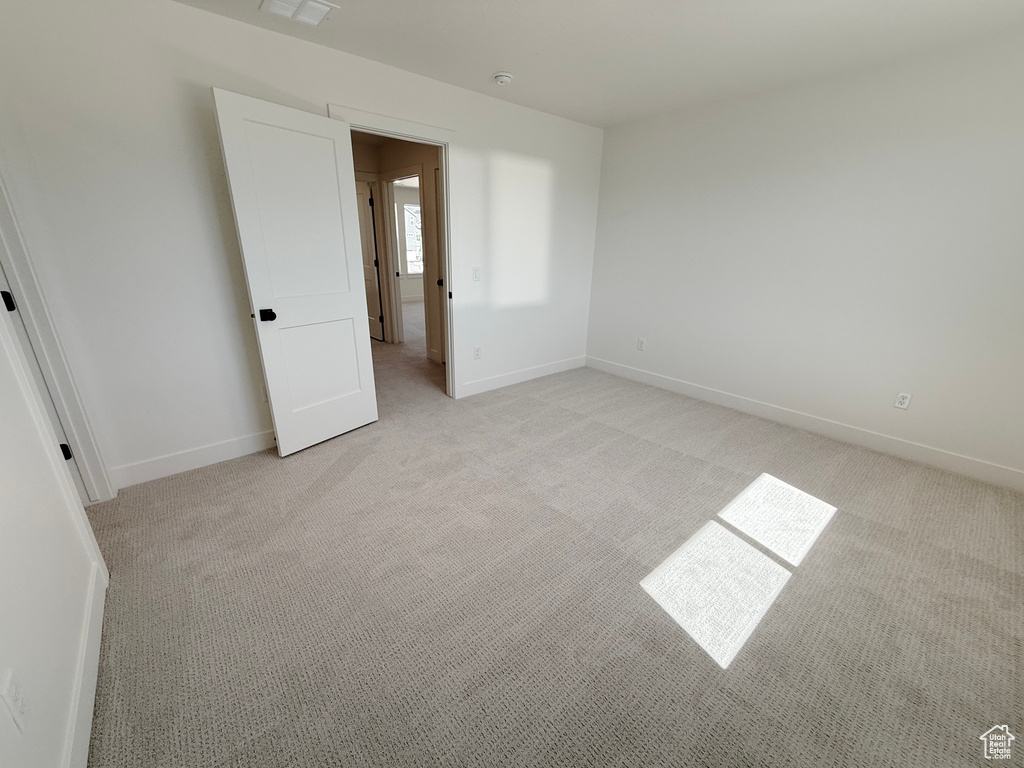 Spare room with light colored carpet, baseboards, and a smoke detector