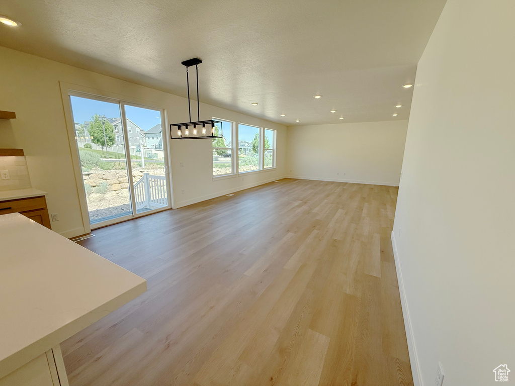 Unfurnished dining area with light wood-style flooring, baseboards, recessed lighting, and a chandelier