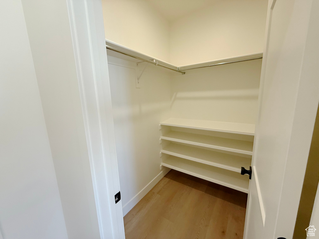 Walk in closet with light wood finished floors