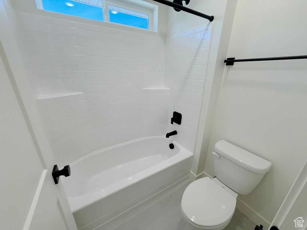 Bathroom with toilet, tub / shower combination, and baseboards