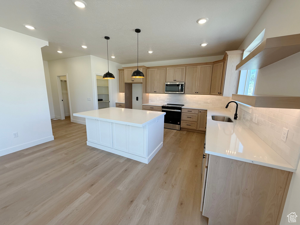 Kitchen featuring appliances with stainless steel finishes, a sink, tasteful backsplash, light countertops, and recessed lighting