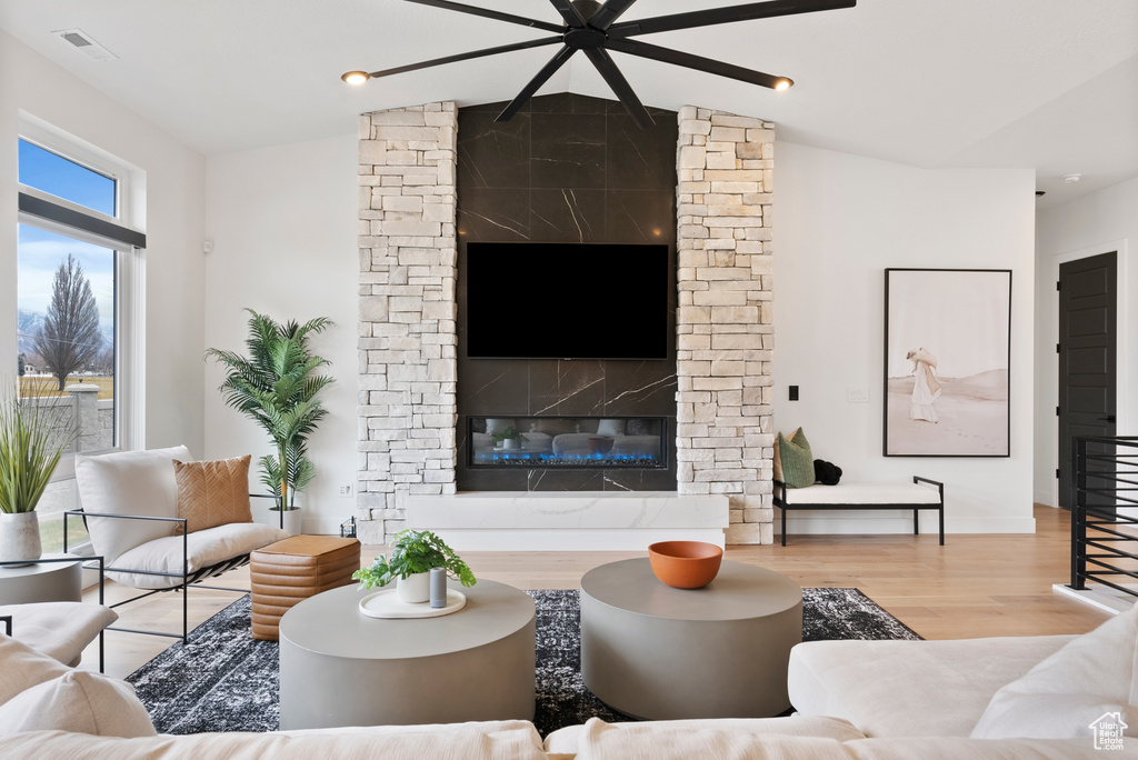 Living room featuring light hardwood / wood-style floors, lofted ceiling, and a fireplace