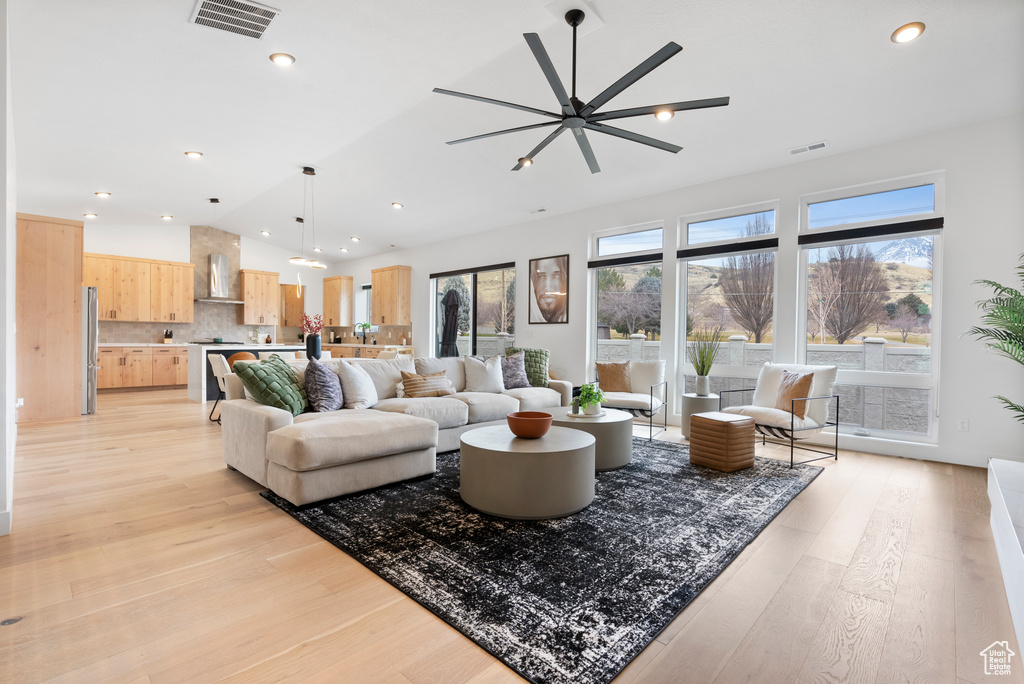 Living room with light wood-type flooring, vaulted ceiling, and ceiling fan