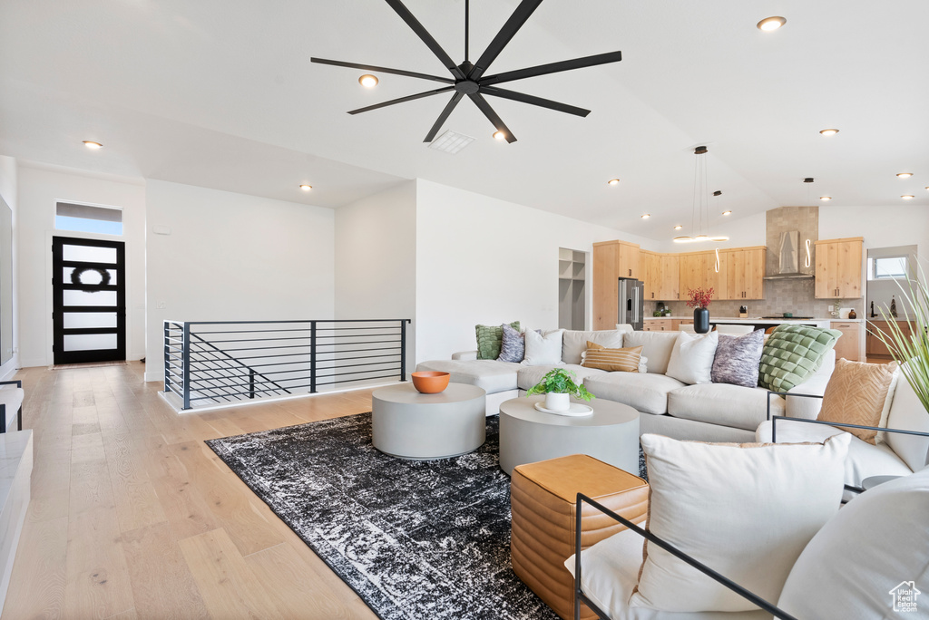 Living room featuring ceiling fan, light wood-type flooring, and vaulted ceiling