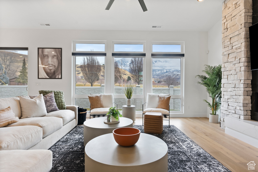 Living room featuring ceiling fan, a fireplace, and light hardwood / wood-style floors